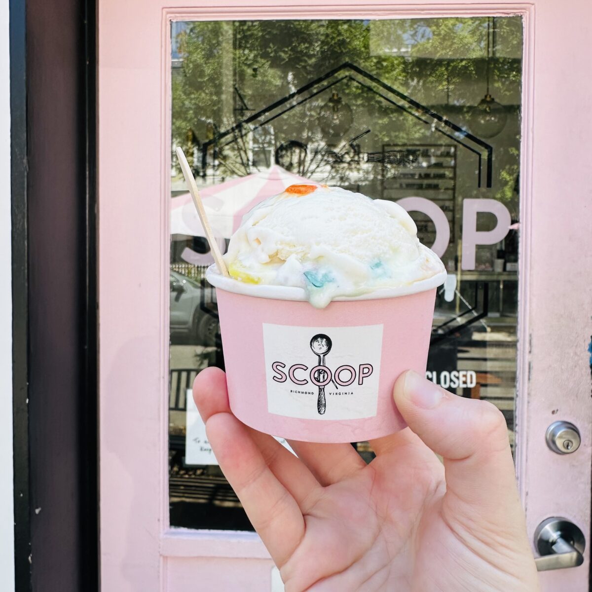 Hand holding cup of ice cream with Scoop logo.