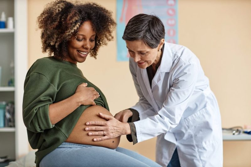 Photo of a doctor examining the stomach of a pregnant woman