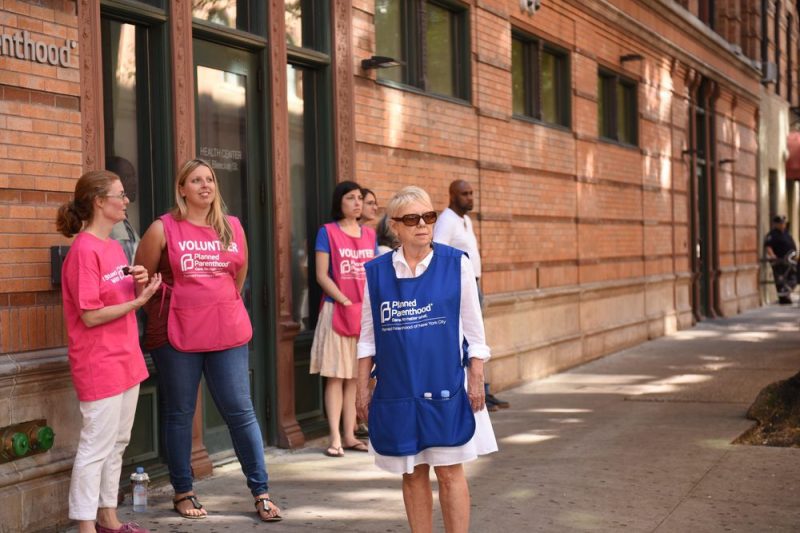 Photo of a Planned Parenthood health care clinic with volunteers standing outside.