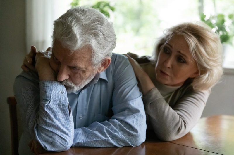 Photo of elder couple worried at a table.